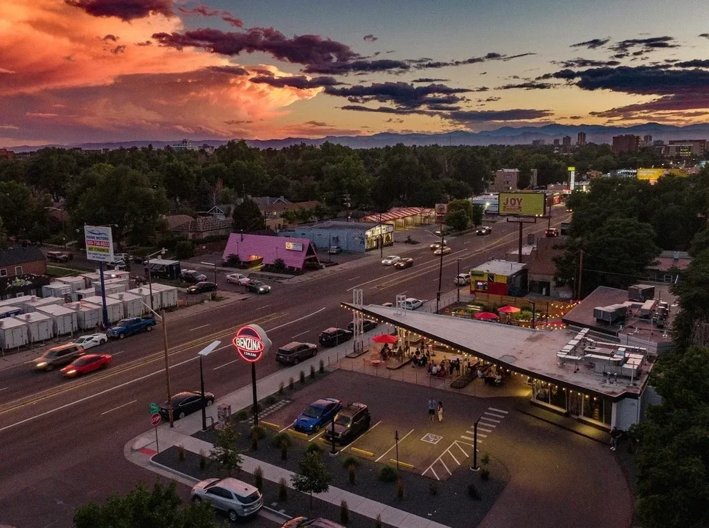 High-angle photo: Bustling Benzina Italian patio, urban street, sunset mountains.