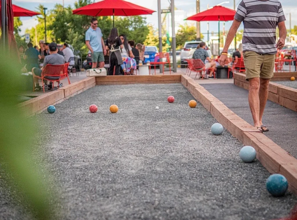 Bocce court with colorful balls, a person, and an outdoor patio.