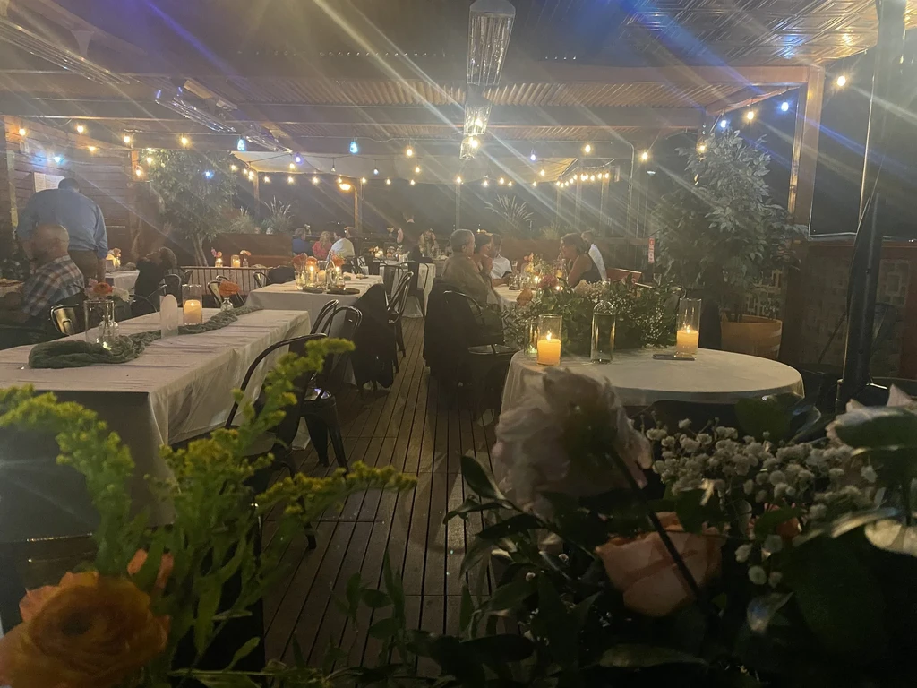 Nighttime outdoor restaurant patio with string lights, candles, and diners.