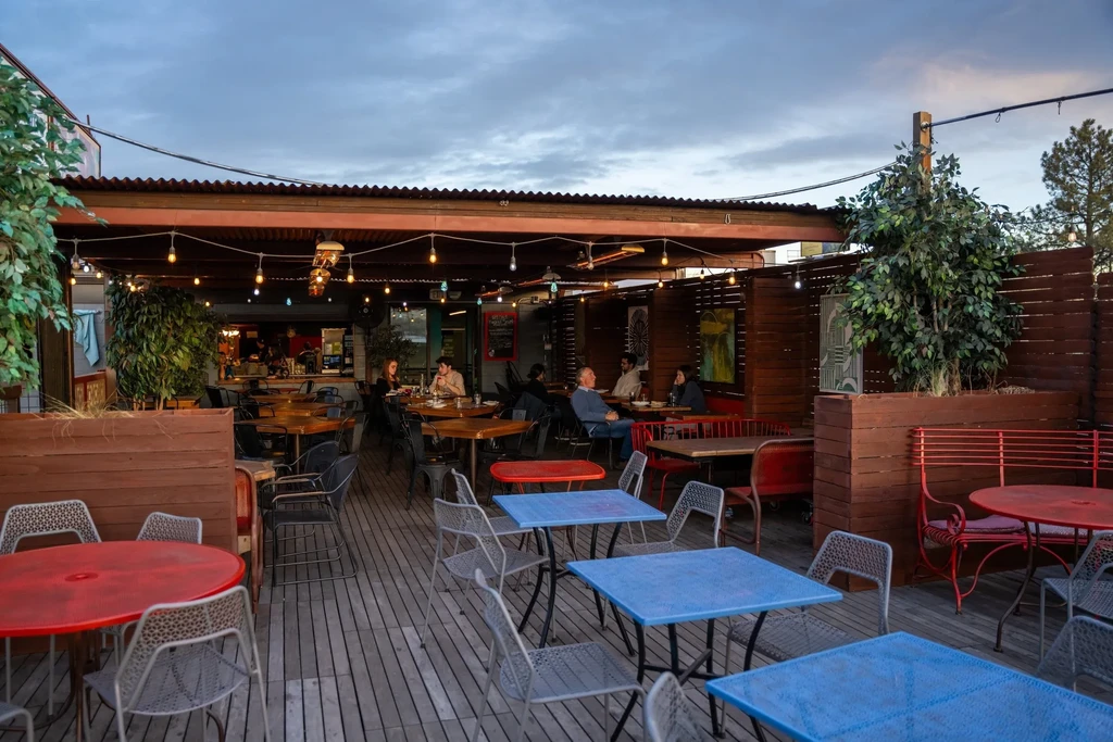Lively outdoor restaurant patio at dusk with string lights and diners.