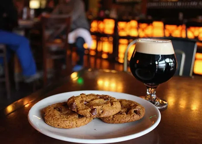 Fresh chocolate chip cookies and stout beer in a cozy bar.
