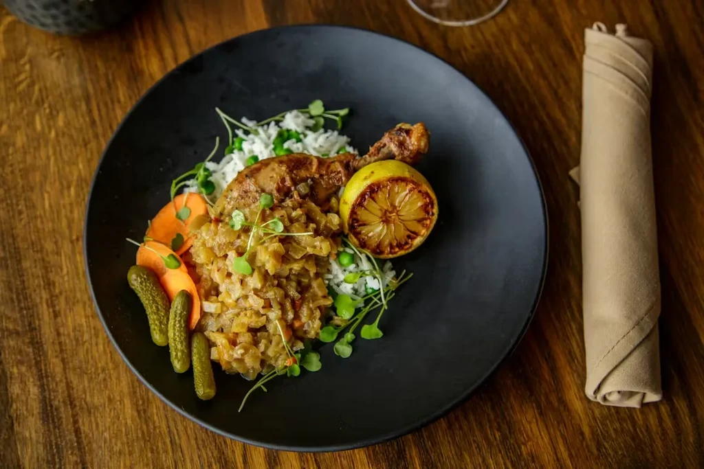 Meticulously plated chicken leg, rice, stew, and vegetables.