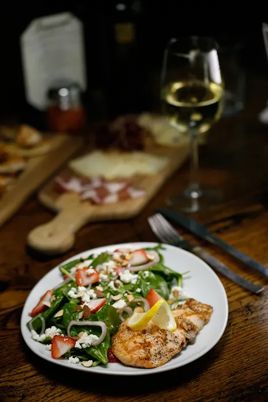Restaurant meal: grilled protein, strawberry salad, wine, and charcuterie board.