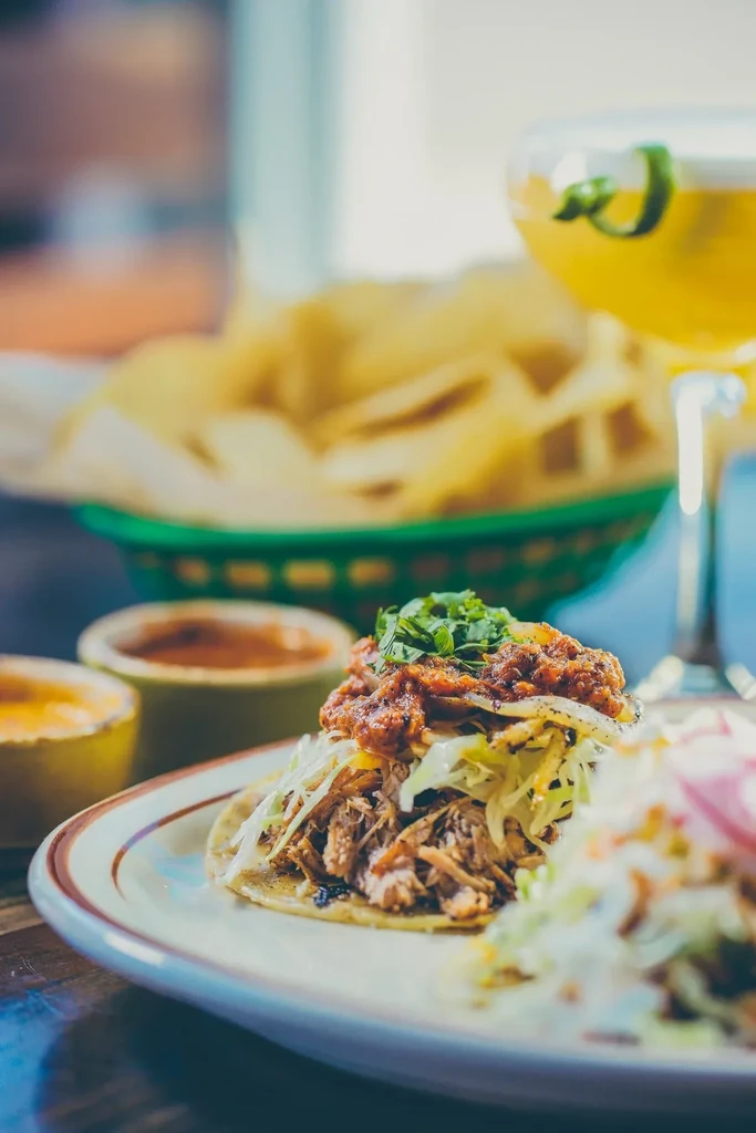 Shredded meat taco topped with salsa and cilantro on a wooden table.