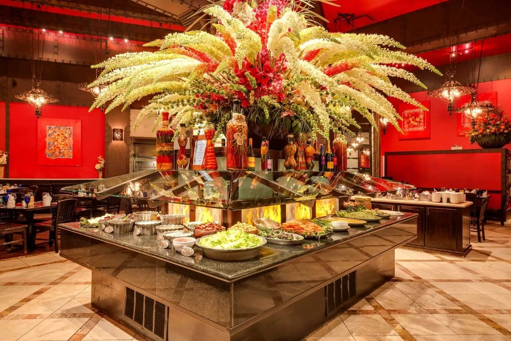 Luxurious restaurant buffet with large floral centerpiece and red walls.