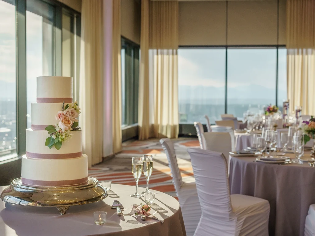 Four-tiered white wedding cake adorned with pink roses and lavender.