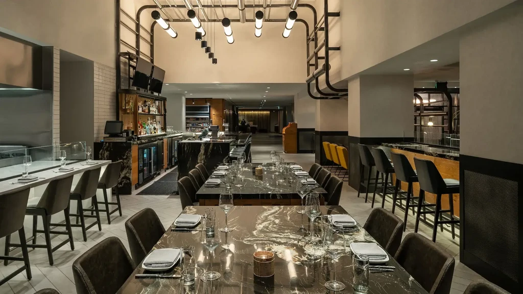 Modern, empty restaurant interior with dining tables, bar, and kitchen.