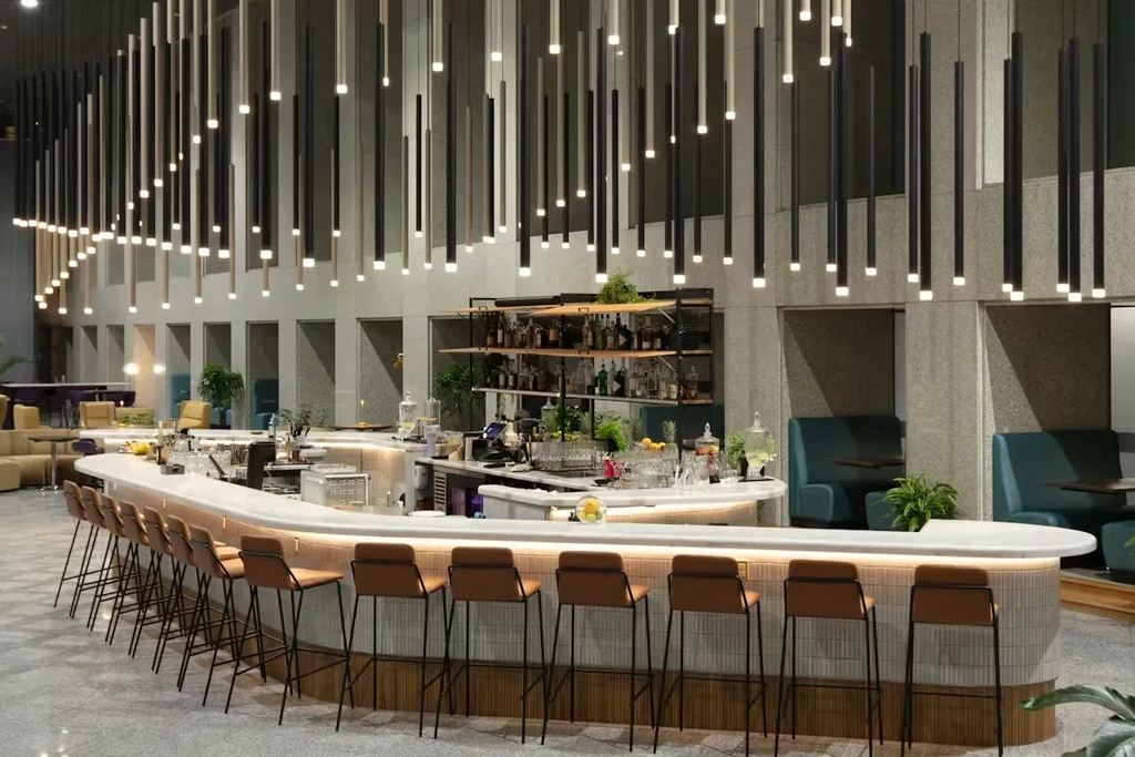 Modern bar with curved counter, brown stools, and pendant lights.