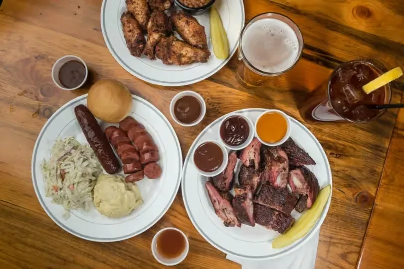Overhead shot of a wooden table with barbecue dishes and drinks.