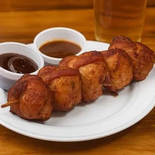 Six fried appetizers, one skewered, with sauces on wood.