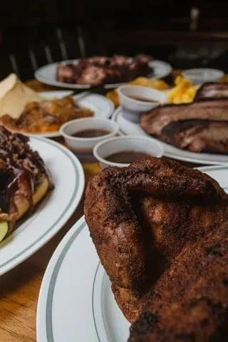 Close-up of a table with crispy barbecue chicken, shredded meat, and brisket.