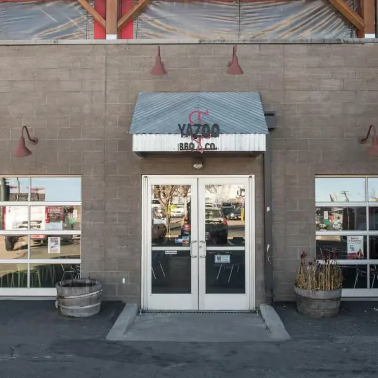 YAZOO BBQ CO. restaurant: grey concrete facade, red awning, exposed wood beams.
