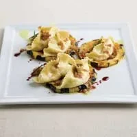 Plated dish: Three folded pasta with garnish, squash, and sauce.