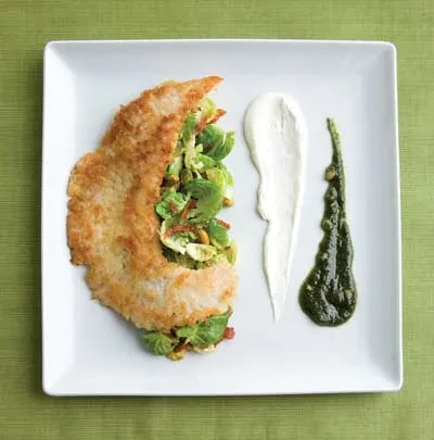 Plated golden cutlet, green Brussels sprouts, and streaked white and green sauces.