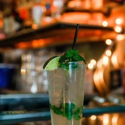Iced cocktail in a tall glass with mint, lime, and condensation.