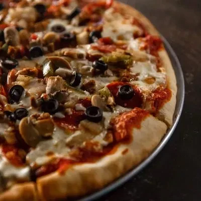 Pizza with cheese, tomato sauce, olives, peppers, mushrooms, and meat.