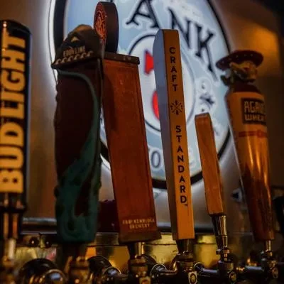 Close-up of diverse beer tap handles at a dimly lit bar.