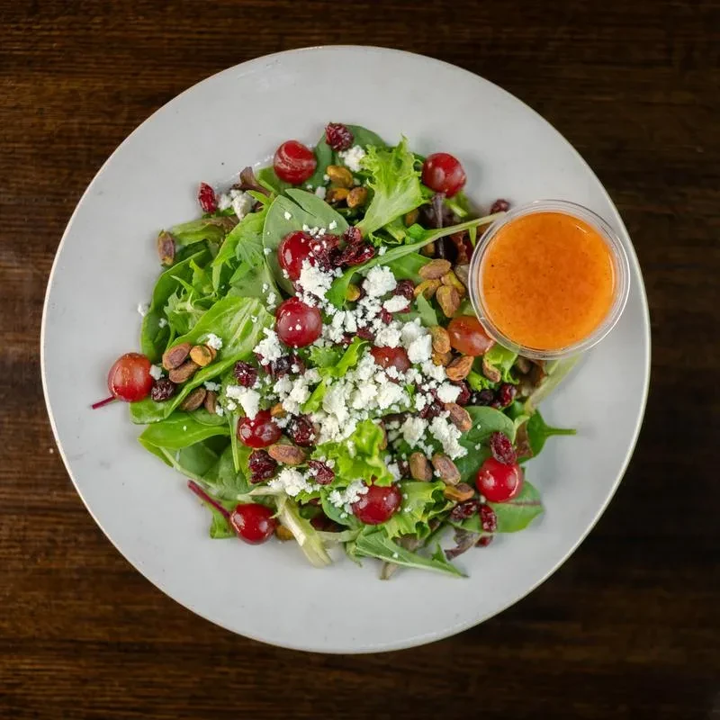 Mixed greens salad topped with cheese, grapes, cranberries, pistachios and dressing.