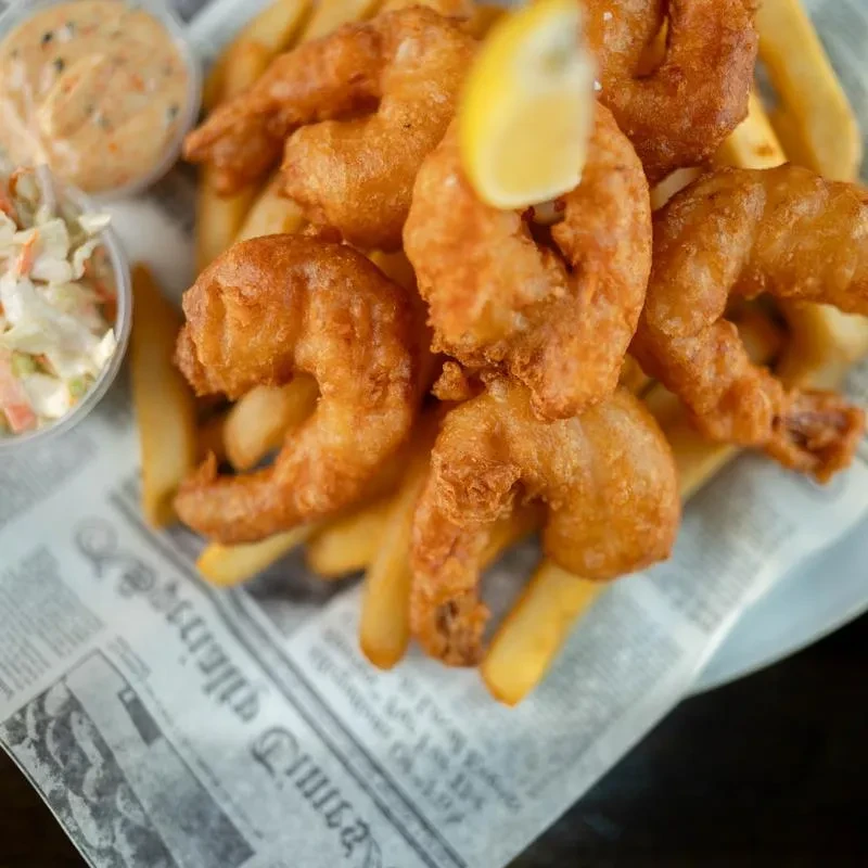 Golden fried shrimp and french fries with lemon, coleslaw, and dipping sauce.