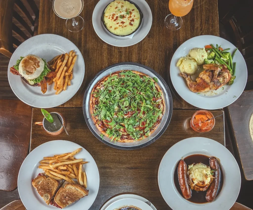 Dark wooden table laden with various restaurant dishes and drinks.
