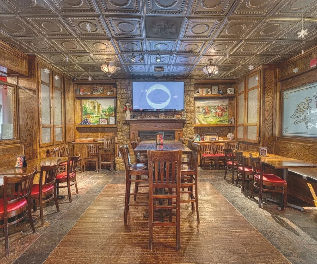 Rustic restaurant interior with ornate ceiling, wood walls, and varied seating.