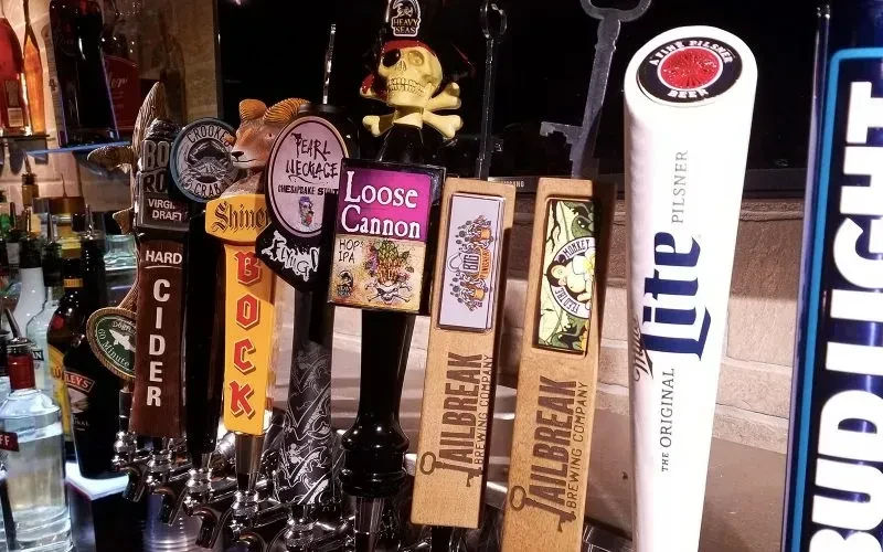 Close-up of unique beer tap handles in a dimly lit bar.
