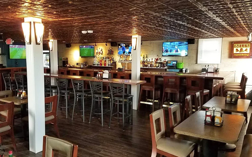 Empty casual bar interior with long wooden bar, sports TVs.