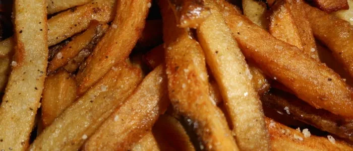 Close-up of golden-brown french fries, seasoned with salt and pepper.