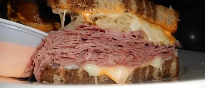 Close-up of a Reuben-style sandwich cross-section with meat, cheese, and sauerkraut.