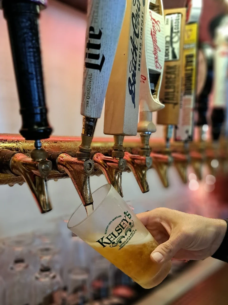 Close-up of beer tap pouring light beer into KELSEY'S glass.