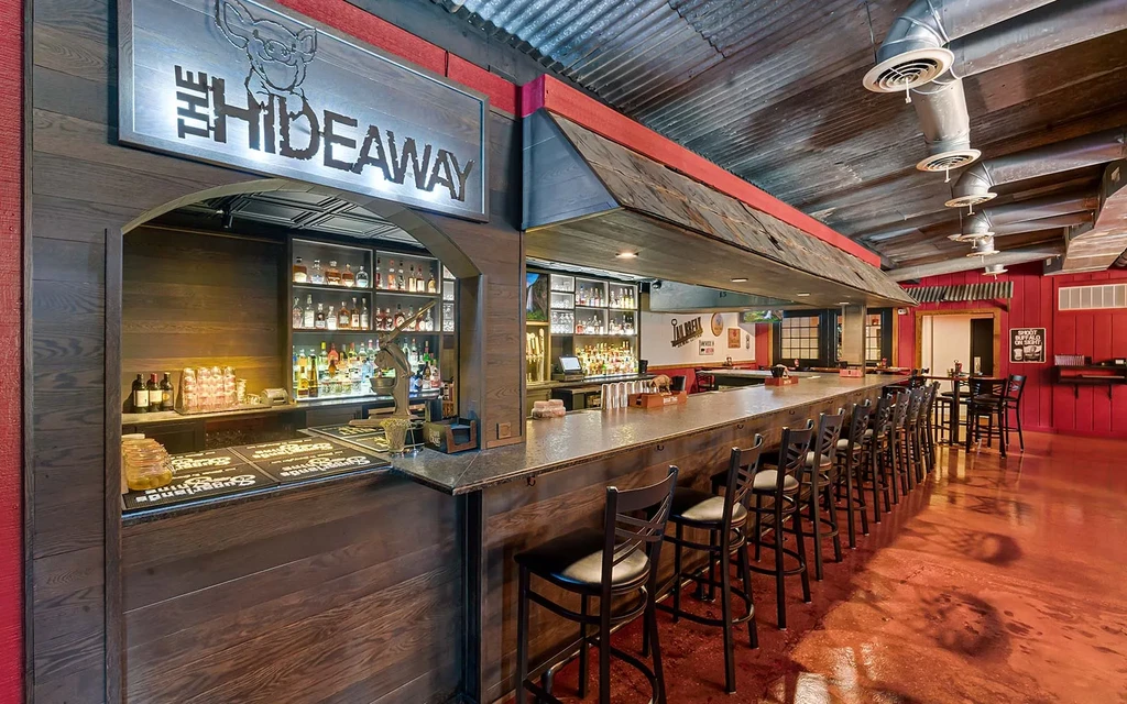 Dark wood bar counter with stools inside 'The Hideaway' bar.