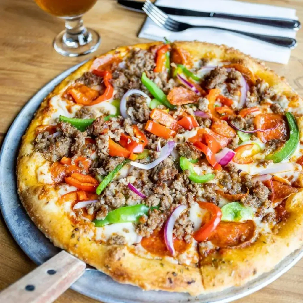 Pizza with sausage, pepperoni, bell peppers, and onions on a pan.