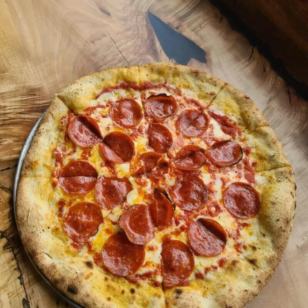 Top-down, sliced pepperoni pizza on a pan and wood table.