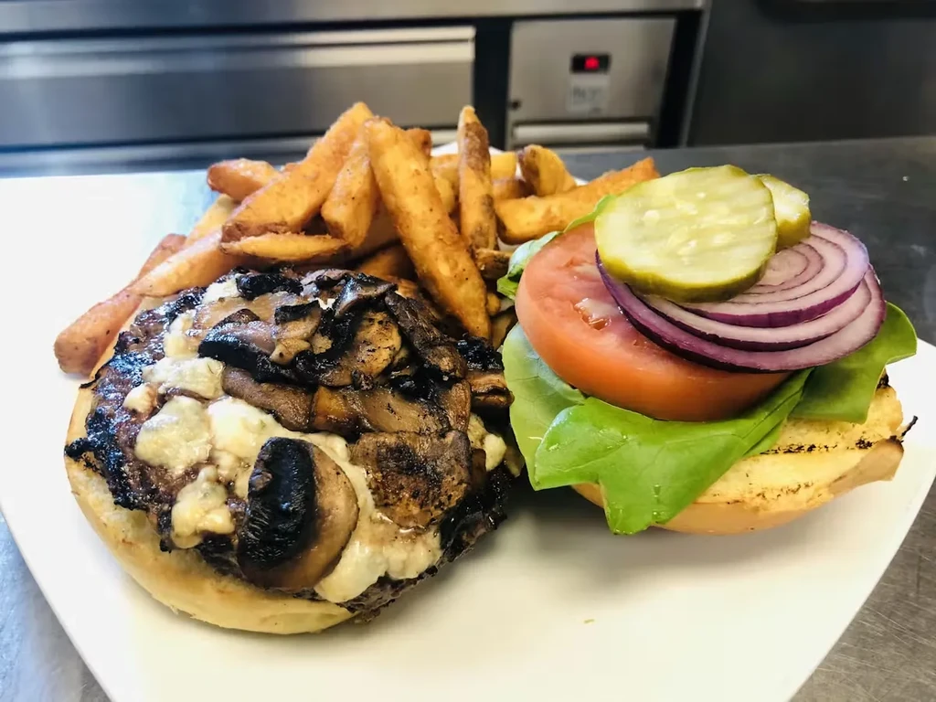Gourmet burger with melted cheese, mushrooms, and a side of french fries.
