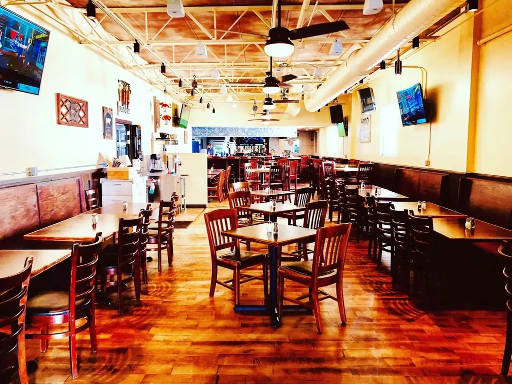 Wide-angle view of a restaurant dining area with tables, booths, and TVs.
