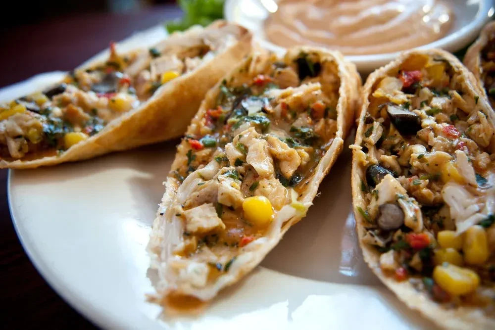 Several chicken taco boats filled with corn and green herbs.