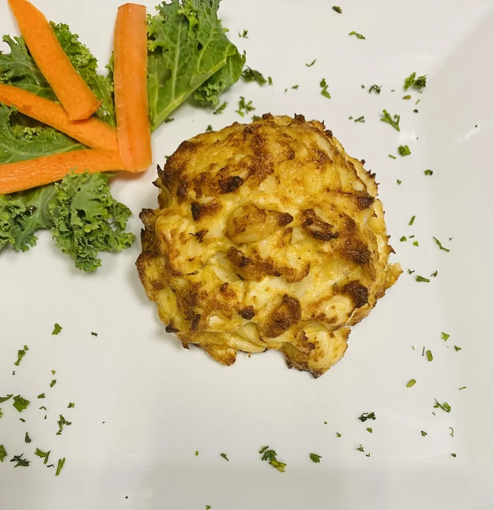 Golden-brown fried patty, garnished with kale and diagonal carrot sticks.