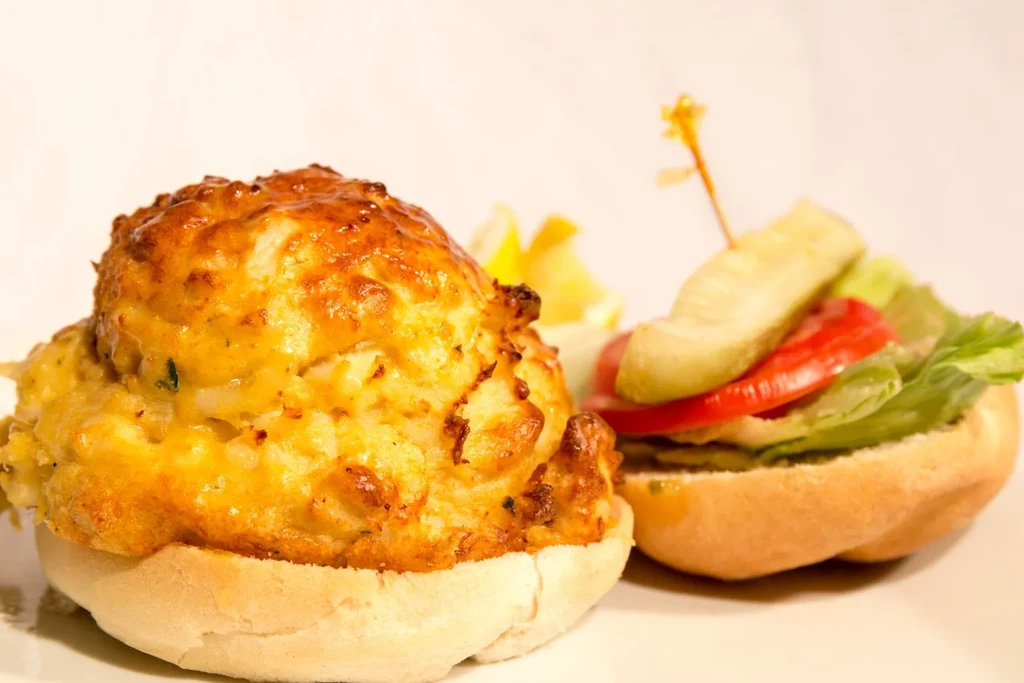 Close-up of a crab cake sandwich and a small slider with vegetables.