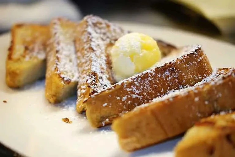 Golden French toast slices with powdered sugar and butter.