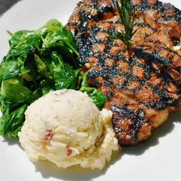 Grilled steak with rosemary, leafy greens, and mashed potatoes.