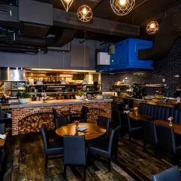 Modern industrial restaurant interior, dark decor, open kitchen, no people.
