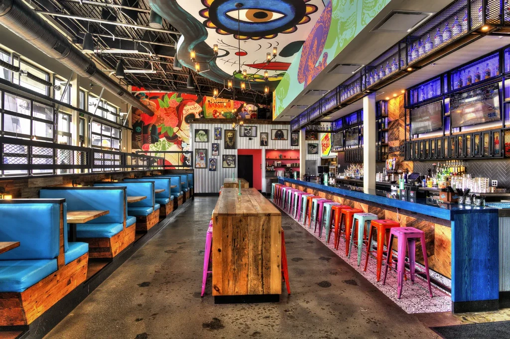 Vibrant, eclectic restaurant interior with murals, industrial features, and bright seating.