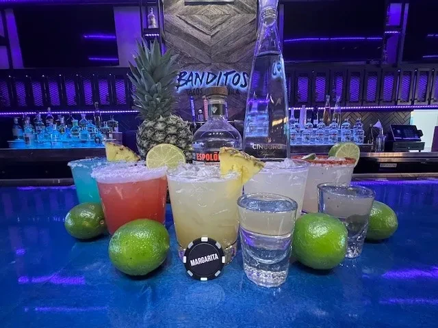 Colorful margaritas and shots at Banditos Tacos on a neon bar.