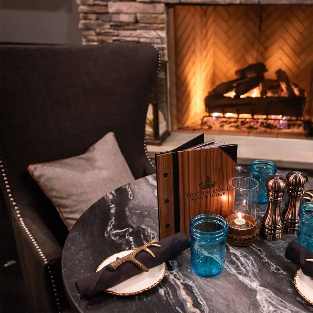 Marble dining table with menu, armchair, and warm fireplace.