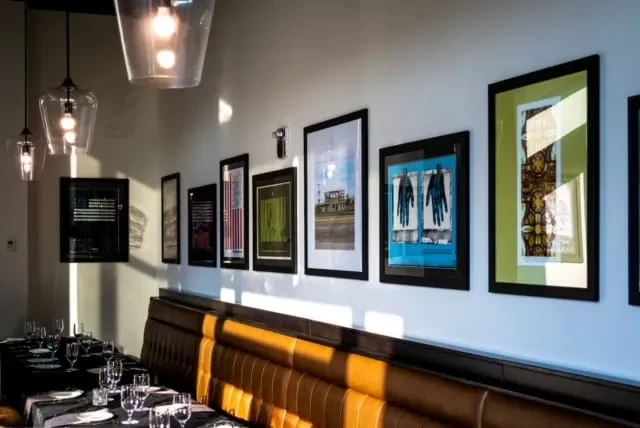 Contemporary restaurant dining area with leather booth, set tables, and framed art.