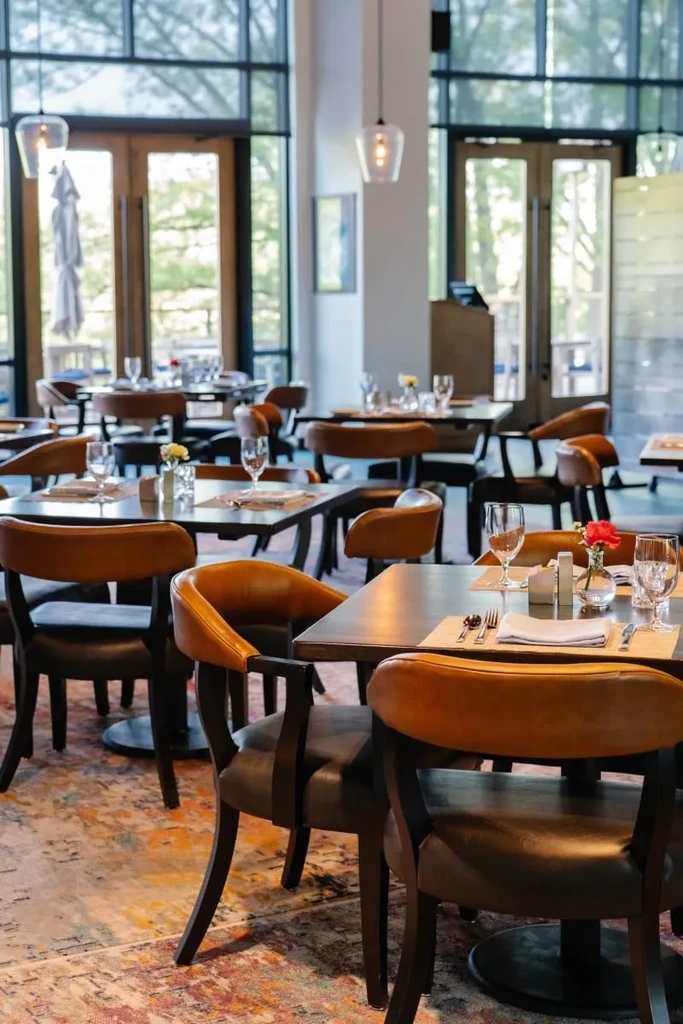 Bright restaurant dining room with set tables and large windows.