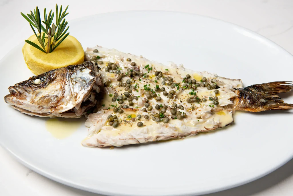 Whole filleted fish, sauced, with capers, herbs, lemon, and rosemary.