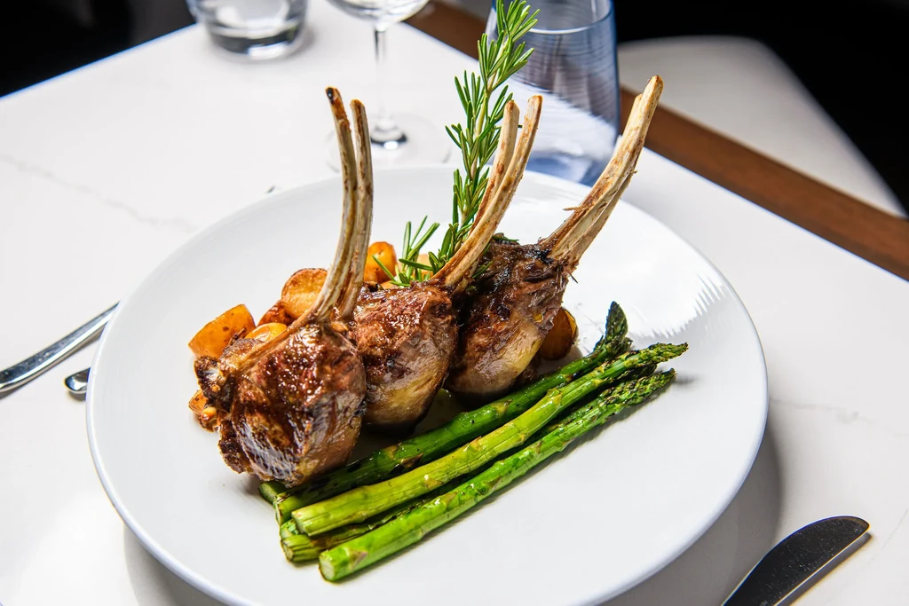 Three upright lamb chops, asparagus, roasted potatoes, and rosemary.
