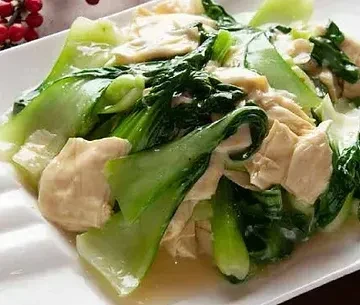 Stir-fried bok choy and tofu skin on a white rectangular plate.