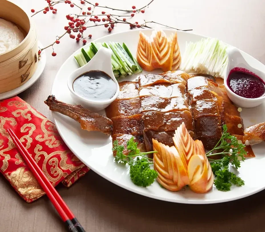 Sliced Peking duck platter with sauces, cucumber, green onions, and pancakes.